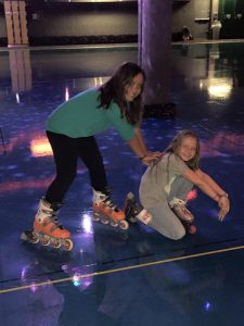 Happy sisters at skating rink wearing roller blades