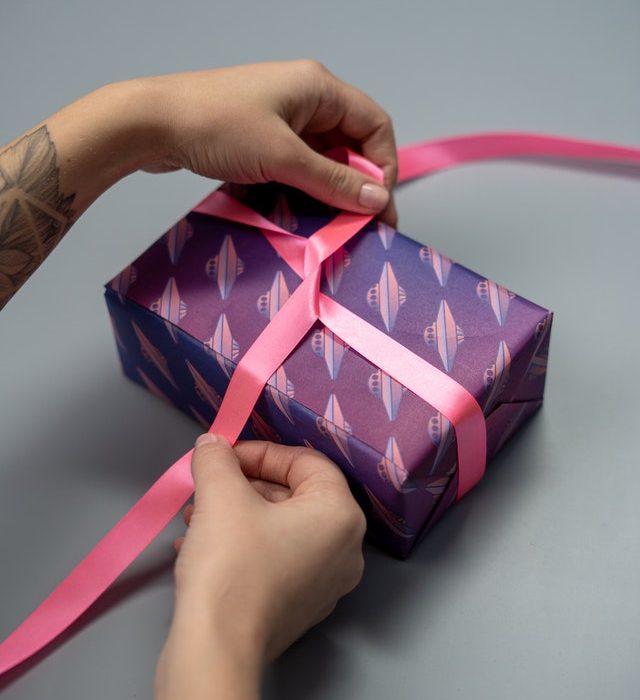 Hands tying bow on wrapped gift