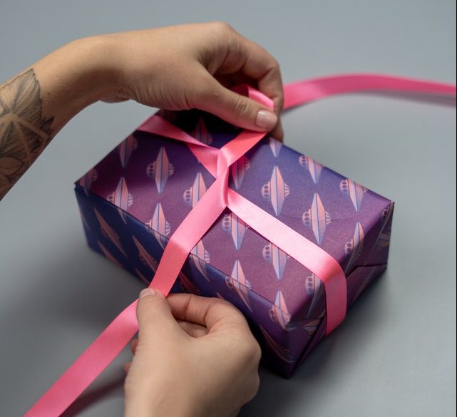 Hands tying bow on wrapped gift