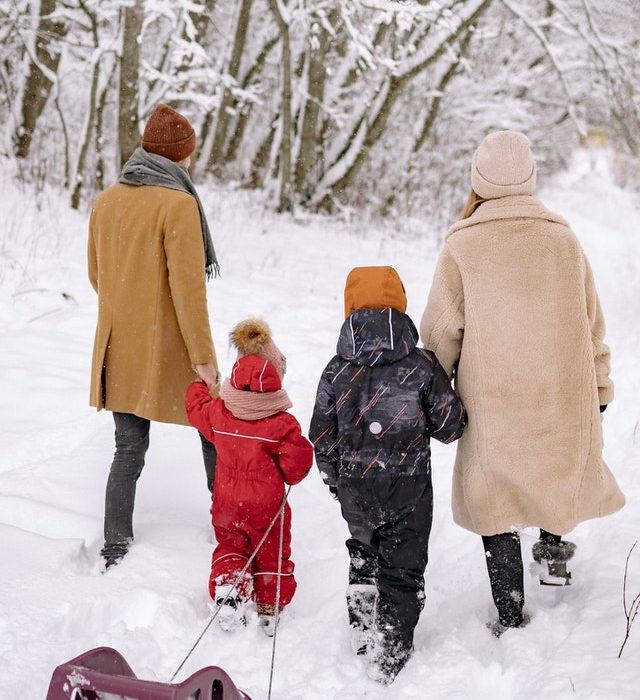 family of four walking in snow with sled