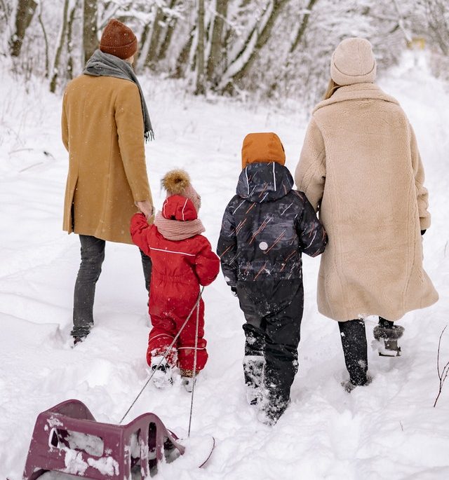 family of four walking in snow with sled